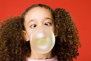little girl blows a bubble gum bubble