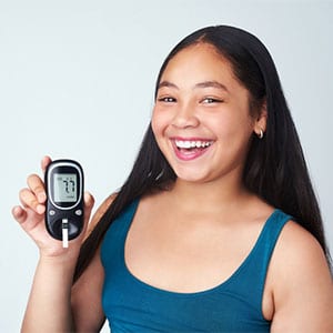 girl smiling with her blood sugar monitor