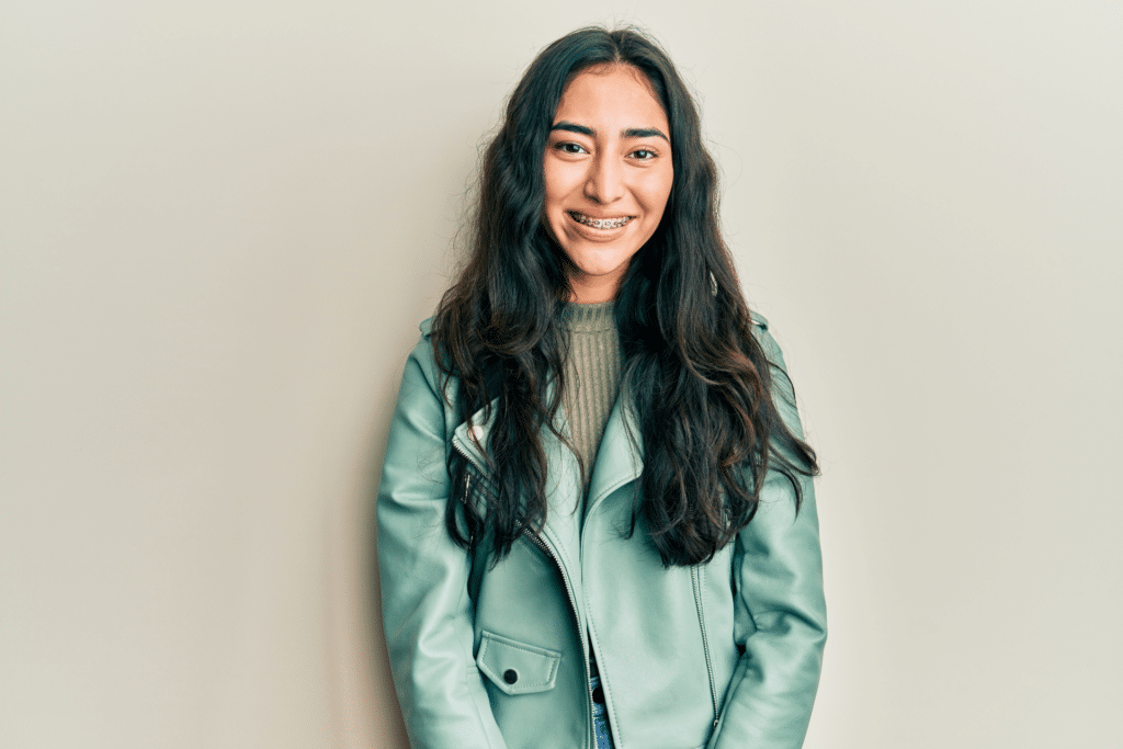 Smiling young woman wearing braces against a light background