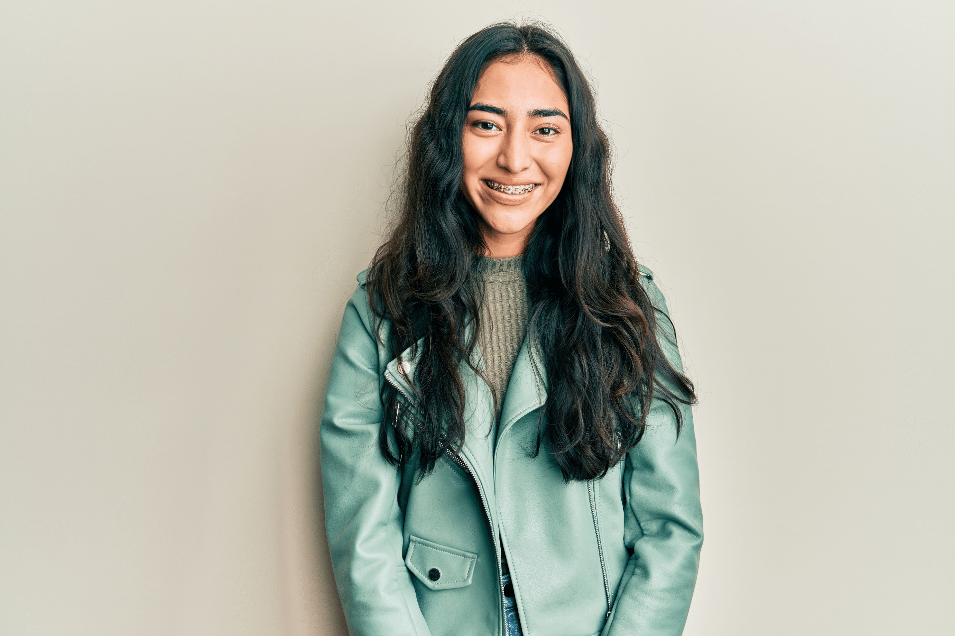 Smiling young woman wearing braces against a light background