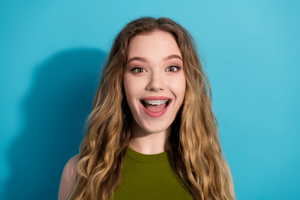 Smiling teenage girl showing her braces against a blue background